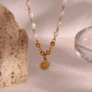 Golden chain necklace featuring freshwater pearls and a vintage sun pendant with face details