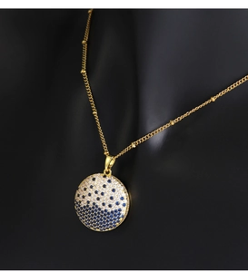 Macro shot of gold planet pendant with blue and white stones on a black model bust