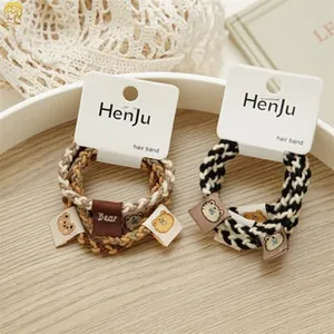 Detail of woven hair bands featuring cute bear tags and branding labels in a dish