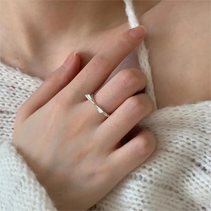 Detail shot of a twisted 925 sterling silver bow ring worn on finger with knit sweater