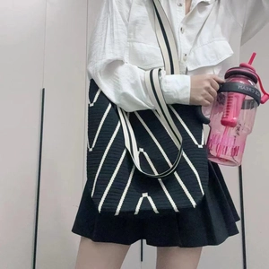 Close-up of a knit tote bag with black and white V-shaped patterns on a female shoulder