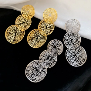 Macro shot of gold and silver hollow geometric round drop earrings on black velvet background