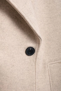 Gros plan sur la texture du manteau en laine avoine et détail d'un bouton noir