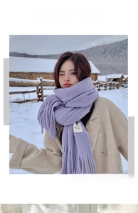 Detail of purple knitted winter scarf with tassels worn by a model in a snowy landscape