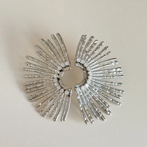 Macro detail of silver sunburst earrings with inlaid white zircon and textured finish