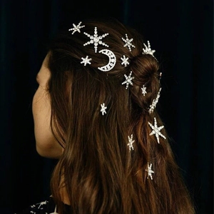 Detailed view of rhinestone star and moon hairpins set in wavy dark hair