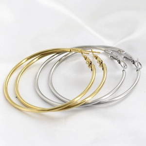 Polished 18K gold and silver stainless steel 50mm hoop earrings on white silk fabric