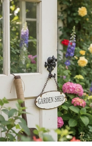 Detail of vintage cast iron garden hook with fleur-de-lis and Garden Shed sign