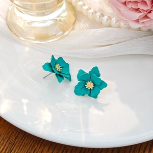 Detailed macro view of layered teal floral stud earrings with golden matte stamens