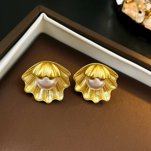 Makro-Detail von Vintage-Gold-Muschelohrringen mit hellrosa Perlen in Schmuckdose