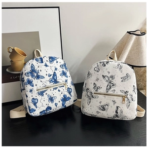 Close-up of butterfly print mini backpacks in white and blue featuring golden hardware