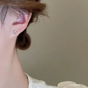Elegant silver butterfly stud earrings with zircon stones worn by a model in a close-up