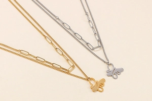 Detail of layered gold and silver necklaces with abstract metal wire butterfly pendants