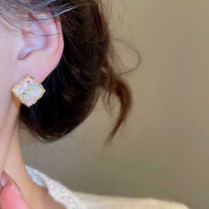 Detail view of a vintage pearl earring featuring pink enamel and floral metalwork