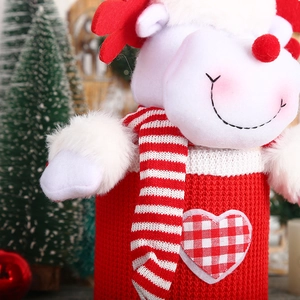 Close-up of red knitted Christmas deer wine bottle cover with heart patch and scarf
