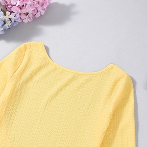 Détail du tissu plissé jaune et de l'encolure sur une robe moulante dos nu sexy