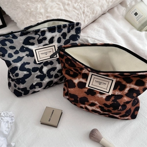 Dettaglio di pochette trucco in tela leopardata con cerniera ed etichetta in tessuto