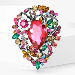 Macro shot of vintage hollow heart brooch with red pear-cut crystal and colorful gems