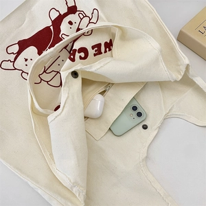 Détail du sac en toile montrant la poche intérieure zippée et le bouton-pression en métal