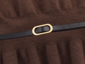 Detailed macro shot of dark brown ribbed knit fabric with a black leather belt and gold buckle