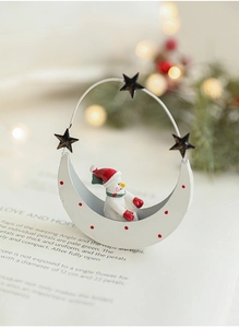 Close-up of a festive moon-shaped snowman ornament with red dots and metal star handle