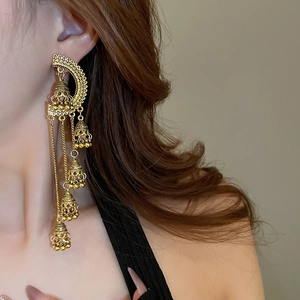 Gros plan de boucles d'oreilles bohèmes dorées avec pompons et cloches sur mannequin