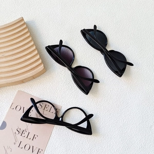 Detail of cat eye kids sunglasses in black frames on a wavy wooden display tray