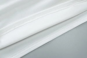 Detail aus weißem Rippstrickstoff mit hochwertigem Doppelnahtsaum und feiner Textur