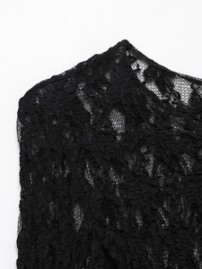 Close-up detail of delicate black floral lace fabric with intricate hollow patterns