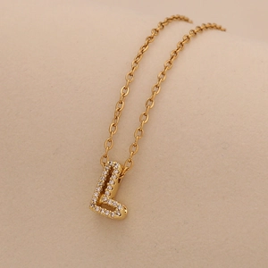 Macro view of gold L-letter pendant necklace with sparkling inlaid cubic zirconia