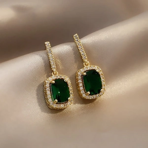 Macro detail of emerald green zircon earrings with golden finish and crystal inlay
