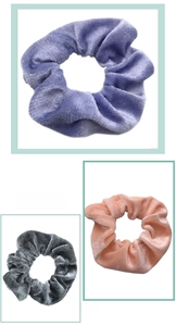 Close-up of velvet scrunchies set in purple, gray and pink with soft pleated texture