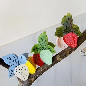 Détail de pinces à cheveux fraise en acétate montrant les textures rouge et rose sur branches