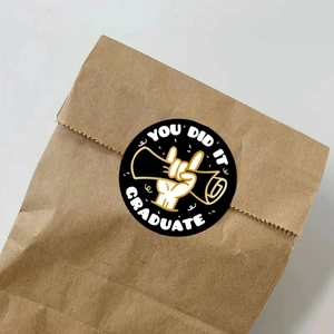 Close-up of black 'YOU DID IT' graduation sticker sealing a kraft paper gift bag
