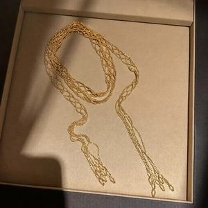 Elegant gold woven lariat necklace with multi-strand fringe tassels in jewelry box