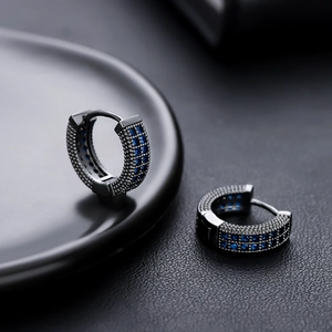 Gros plan de créoles en bronze avec des pierres de zircone cubique bleues