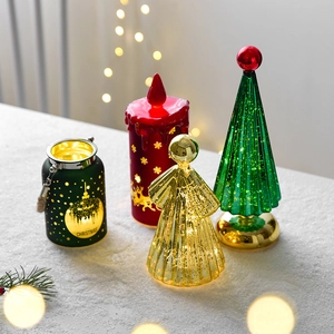Illuminated glass Christmas tree and lantern set with LED lights on snowy surface