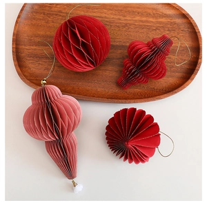 Detail of red and pink honeycomb paper Christmas tree ornaments with golden strings