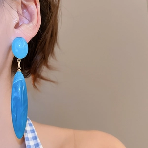 Close-up of sky blue marble acrylic drop earring with gold connector on model