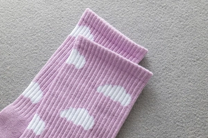 Detailed close-up of purple knitted socks featuring white cloud pattern and ribbed cuffs