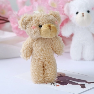 Close-up of curly plush teddy bear pendant with pink blush cheeks and ribbon loop