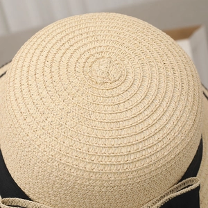 Dettaglio della trama a spirale del cappello di paglia beige con nastro nero decorativo