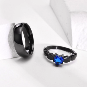 Detail shot of black titanium couple rings featuring a blue heart-shaped gemstone inlay