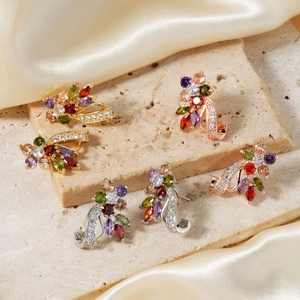 Three pairs of floral earrings in gold, rose gold, and silver with vibrant colored gemstones