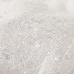 Dettaglio macro del tessuto avorio con paillettes e perline luccicanti su tulle