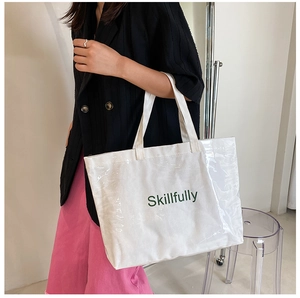 Close-up of white canvas tote bag with clear PVC layer and green Skillfully print