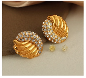 Macro detail of vintage gold-plated wing earrings with sparkling rhinestone pavé setting