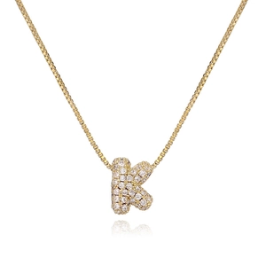 Close-up of gold bubble letter K pendant with cubic zirconia on box chain