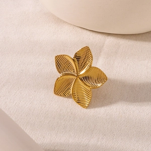 Minimalist golden flower ring with textured petals on an elegant beige fabric background