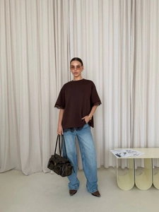 Detail of lace trim on dark brown t-shirt cuffs and hem paired with blue wide jeans